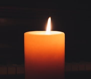 Close-up of a glowing candle in the dark, highlighting warmth and serenity.